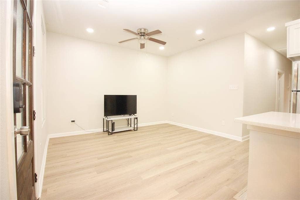 Neutral-toned interior featuring wood-finish flooring, recessed lighting, a ceiling fan, and a wood-paneled door with glass inserts