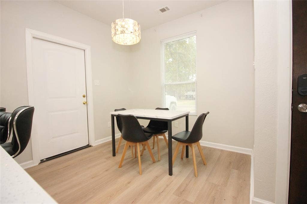 Wood-finish flooring, neutral wall tones, decorative drum pendant lighting, and a single vertical window