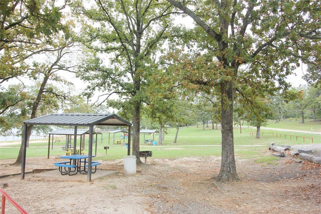 Expansive grounds featuring mature shade trees, metal-roofed pavilions, and open green space