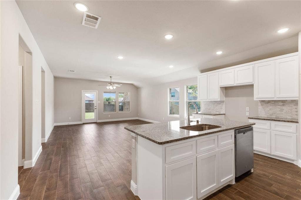 1253 Carinna Drive, Anna, TX 75409 Kitchen featuring a central island with stone countertop, stainless steel dishwasher, white cabinetry, tile backsplash, and wood-finish flooring