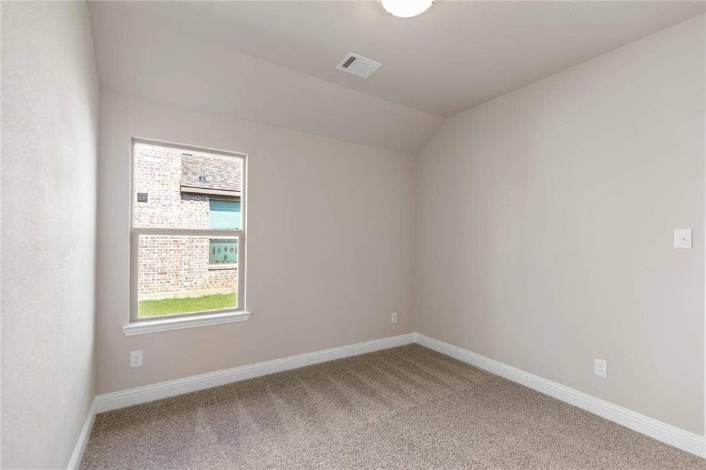 1253 Carinna Drive, Anna, TX 75409 Neutral-toned interior room featuring wall-to-wall carpeting, vaulted ceilings, and a single window with a view of a brick exterior