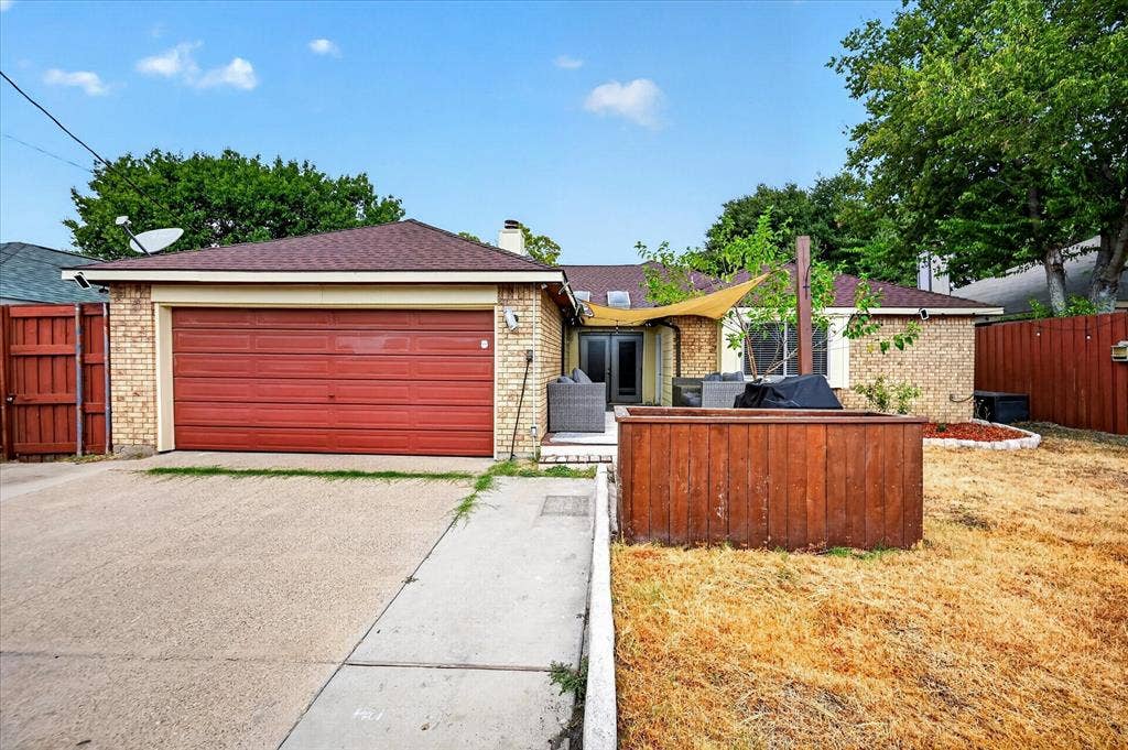 Brick exterior facade with an attached two-car garage, concrete driveway, and solid wood privacy fencing