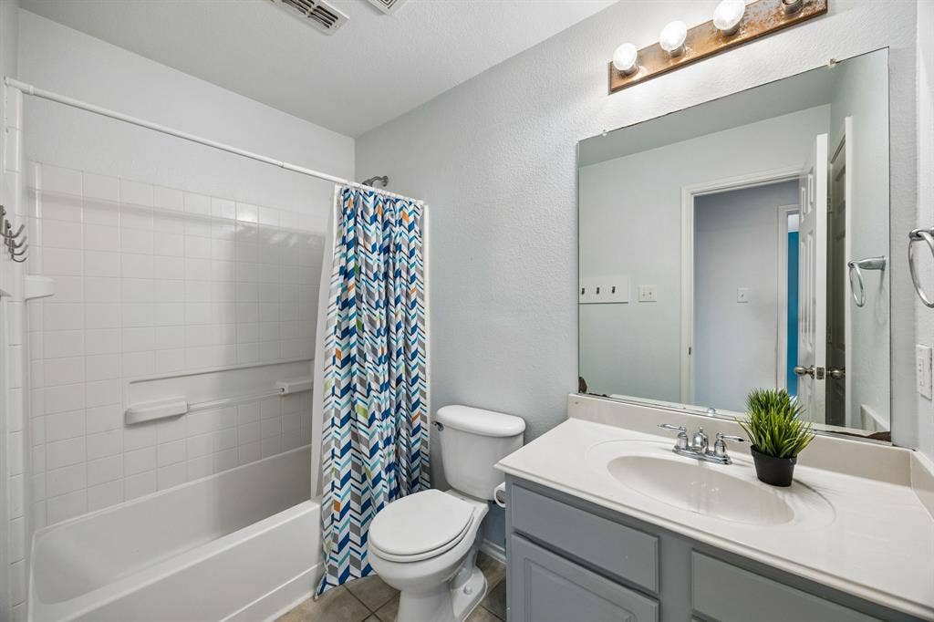 861 Crockett Drive, Lavon, TX 75166 A well-appointed 2nd floor full bathroom featuring a tub and shower combination with white tile surround, a spacious vanity with a white countertop, and a large mirror that enhances the room's bright, open feel. Neutral finishes and ample lighting create a clean, functional space, while the practical layout provides everyday convenience.