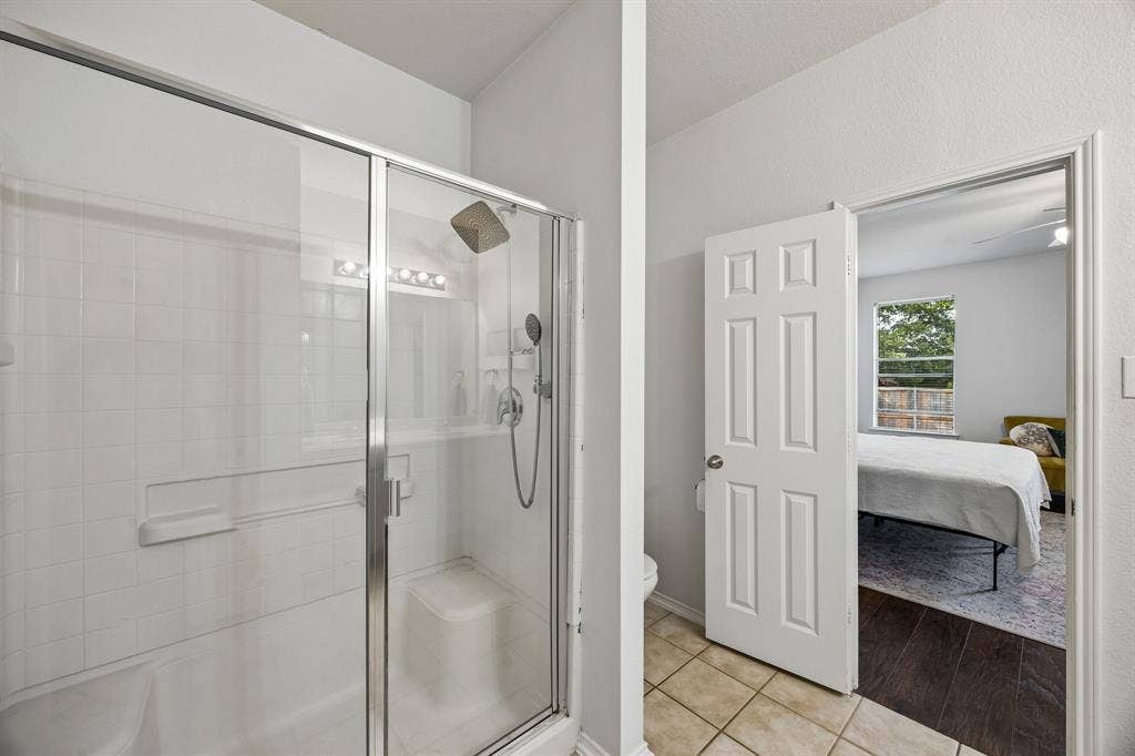861 Crockett Drive, Lavon, TX 75166 A glass-enclosed shower features tiled walls, chrome-finished fixtures, and a spacious interior designed for everyday comfort. The glass doors create an open feel while allowing light to flow throughout the bathroom. Conveniently attached to the primary bedroom, this ensuite offers a practical layout that you'll enjoy.