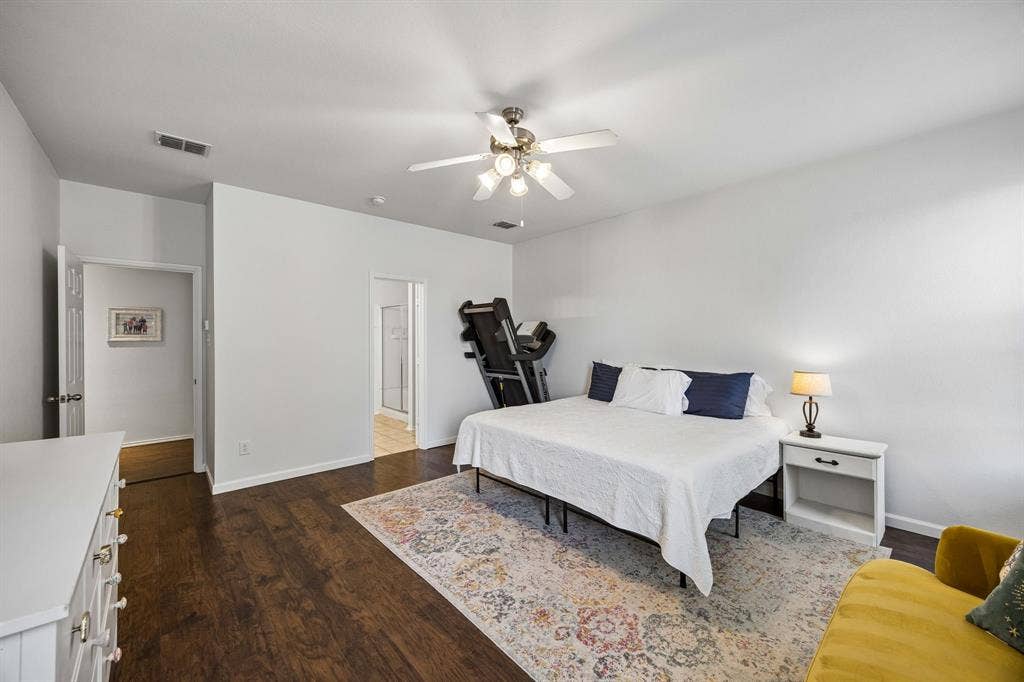 861 Crockett Drive, Lavon, TX 75166 This generously sized primary bedroom with attached ensuite features warm wood-look flooring, neutral finishes, and a ceiling fan with integrated lighting. The room's spacious layout and understated finishes create a comfortable setting with room to make it your own.