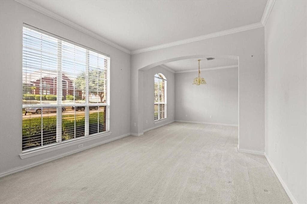 4120 Silverthorne Street, Richardson, TX 75082 Neutral interior space featuring arched architectural detailing, crown molding, expansive windows, wall-to-wall carpeting, and a multi-arm chandelier