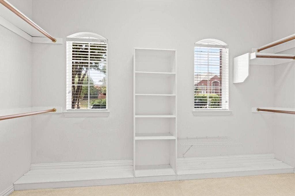 4120 Silverthorne Street, Richardson, TX 75082 Walk-in closet featuring dual arched windows, built-in shelving, white integrated cabinetry, and metal hanging rods