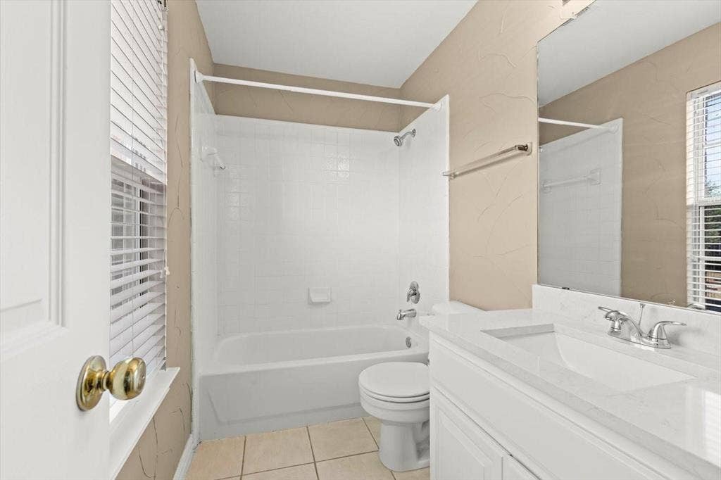 4120 Silverthorne Street, Richardson, TX 75082 Bathroom featuring a vanity with a countertop, integrated basin, and polished chrome faucet, alongside a tub-shower combination with tile surround and tile flooring