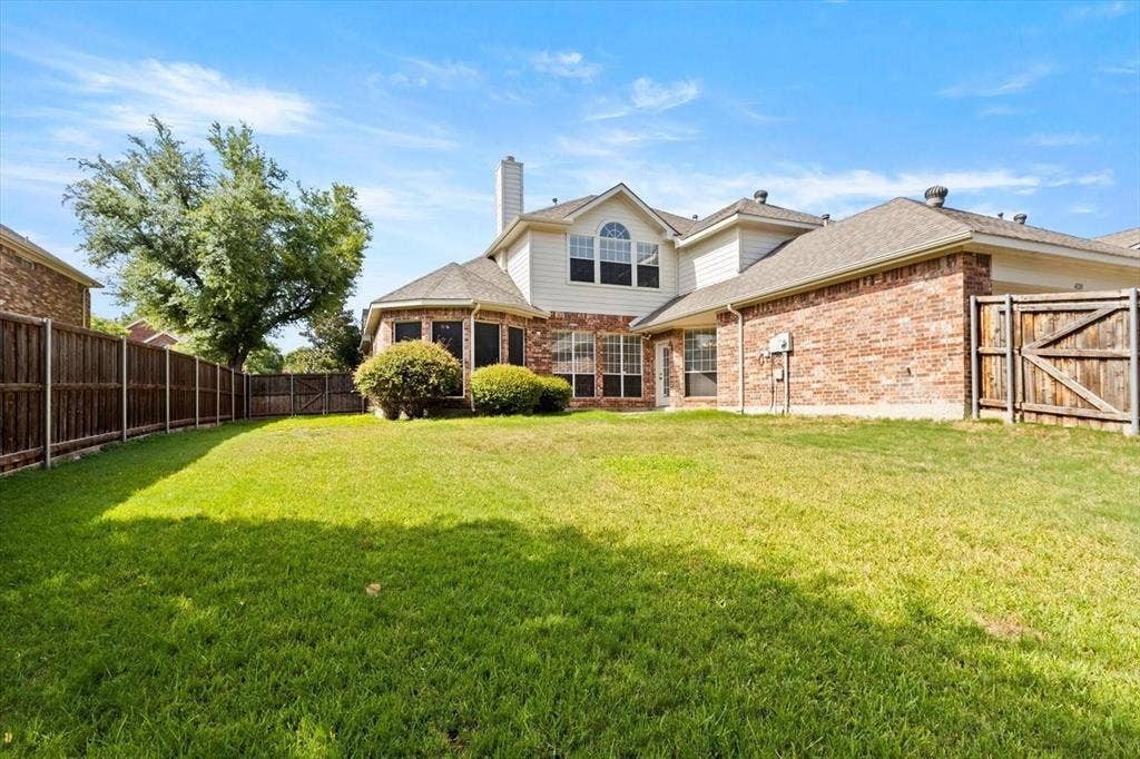 4120 Silverthorne Street, Richardson, TX 75082 Rear exterior featuring a brick and siding facade, expansive lawn, mature landscaping, and wood privacy fencing