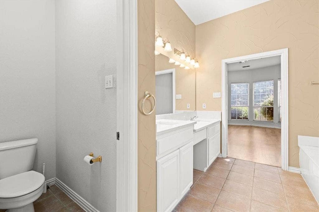 4120 Silverthorne Street, Richardson, TX 75082 Bathroom featuring a dual-sink vanity with white cabinetry, ceramic tile flooring, a large wall-mounted mirror, and multi-bulb overhead lighting