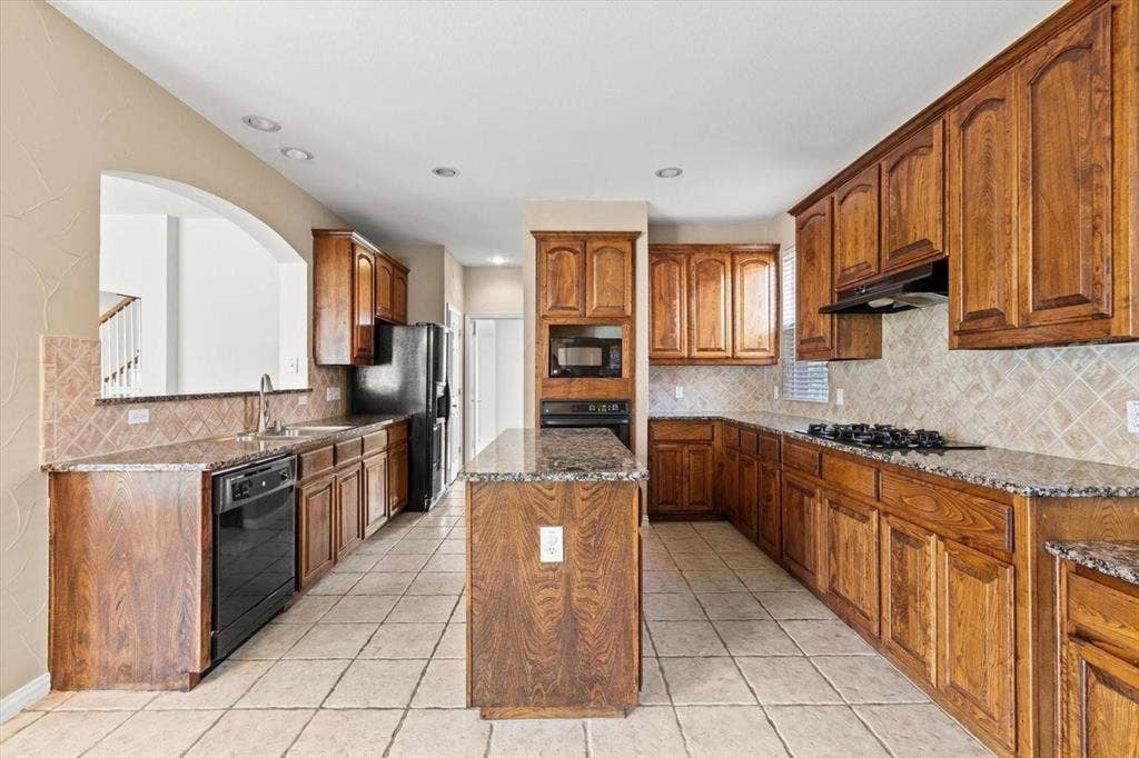 4120 Silverthorne Street, Richardson, TX 75082 Kitchen featuring wood cabinetry, stone countertops, central island, tile backsplash, and recessed lighting