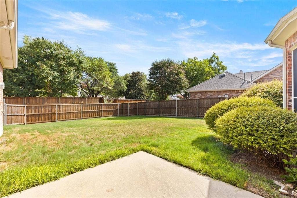 4120 Silverthorne Street, Richardson, TX 75082 Rear exterior area featuring a concrete patio, wood privacy fencing, a manicured lawn, and mature landscaping
