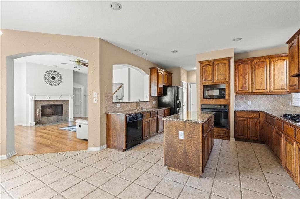 4120 Silverthorne Street, Richardson, TX 75082 Kitchen featuring stained wood cabinetry, stone-finish countertops, a center island, recessed lighting, and tile flooring