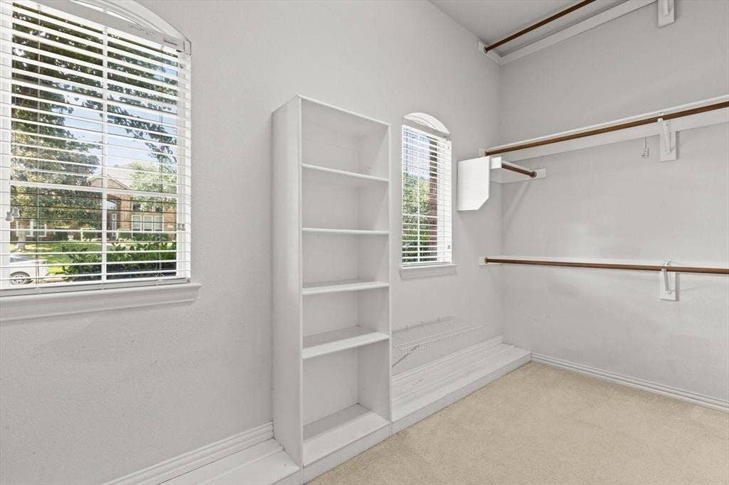4120 Silverthorne Street, Richardson, TX 75082 Walk-in closet featuring built-in shelving, dual-level hanging rods, and arched windows with horizontal blinds