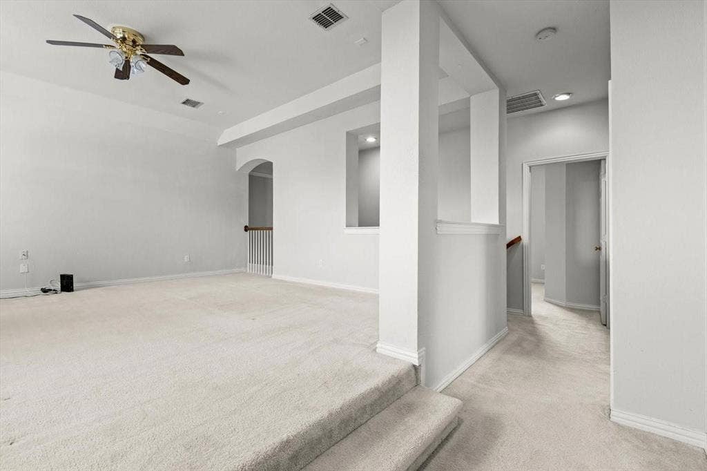 4120 Silverthorne Street, Richardson, TX 75082 Multi-level room featuring wall-to-wall carpeting, elevated platform area, ceiling fan with light fixture, architectural cut-out wall, and staircase with wooden handrail
