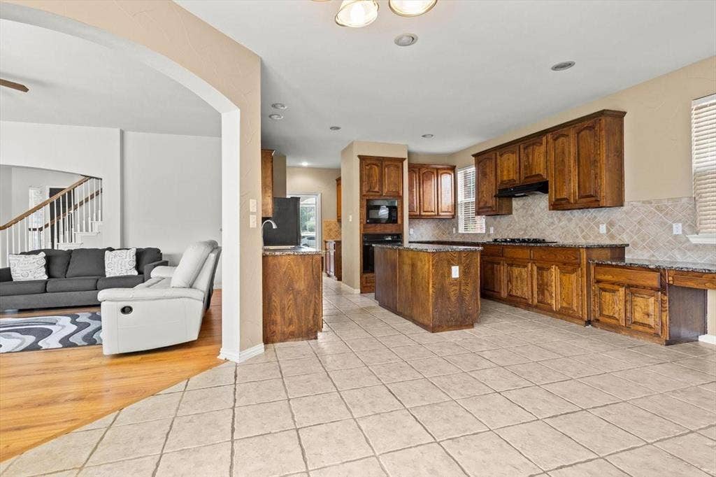 4120 Silverthorne Street, Richardson, TX 75082 Kitchen featuring stained wood cabinetry, central island, stone-finish countertops, tiled backsplash, and recessed lighting