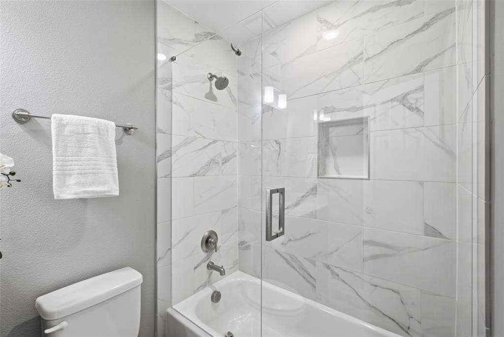 4010 Azure Lane, Addison, TX 75001 The shower-tub combo has floor-to-ceiling marble-look tile, a built-in niche and frameless glass. Spa style for every day.