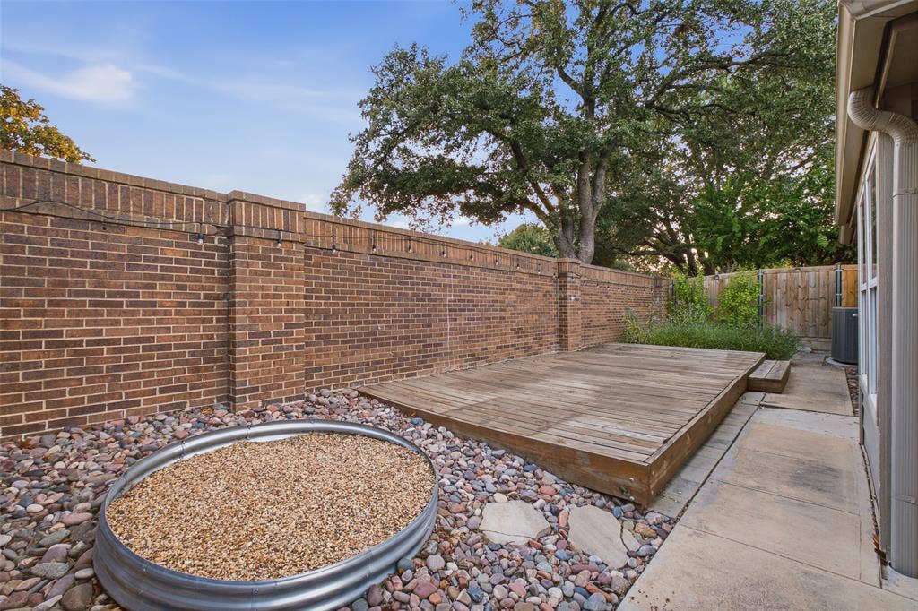 4010 Azure Lane, Addison, TX 75001 A brick privacy wall, a wood deck and a gravel fire-feature area surrounded by river rock and shaded by mature oaks. Your backyard escape.