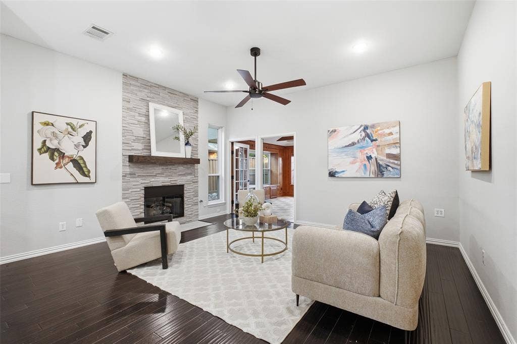 4010 Azure Lane, Addison, TX 75001 The stone fireplace anchors a living room designed for cozy nights in and easy entertaining, framed by tall windows and dark wood floors.
