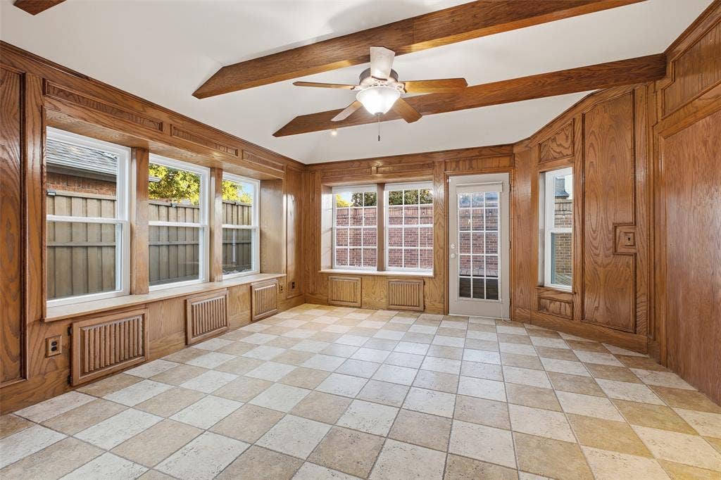 4010 Azure Lane, Addison, TX 75001 The sunroom is surrounded by windows, with warm wood paneling, beamed ceilings and built-in window seats. A one-of-a-kind retreat for reading, games or morning sun.