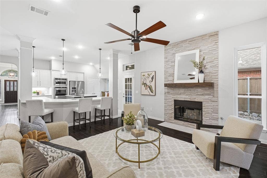 4010 Azure Lane, Addison, TX 75001 The heart of the home: the living room opens straight to the kitchen, with a floor-to-ceiling stacked-stone fireplace, wood-beam mantel and recessed lighting.