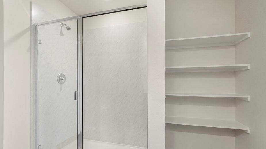 708 Rock Point Road, Josephine, TX 75135 Shower enclosure with clear glass door, chrome showerhead, and circular control, accompanied by built-in shelving