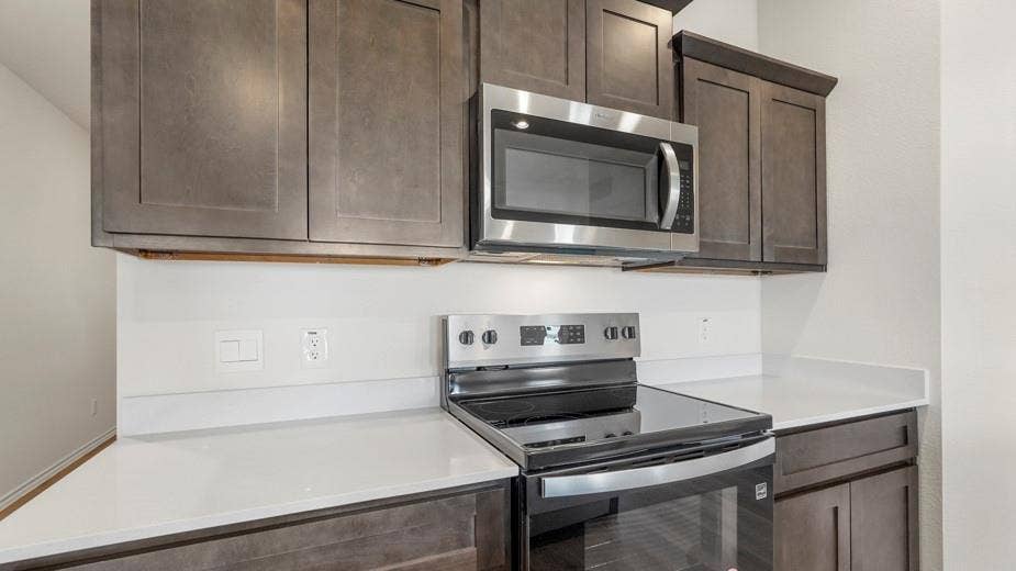 708 Rock Point Road, Josephine, TX 75135 Gray shaker-style cabinetry with crown molding, stainless steel microwave, electric range, and light-toned countertops