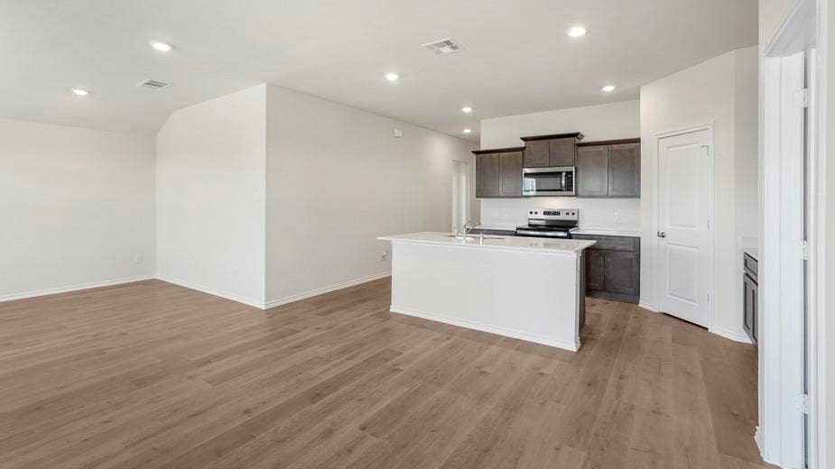708 Rock Point Road, Josephine, TX 75135 Expansive wood-finish flooring throughout, recessed lighting, kitchen island with built-in sink, dark wood cabinetry, and stainless steel appliances