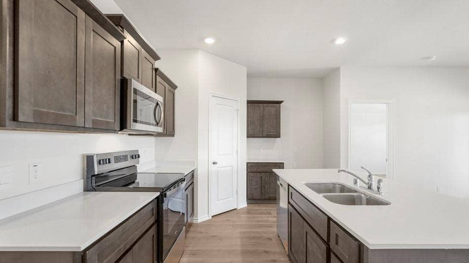 708 Rock Point Road, Josephine, TX 75135 Kitchen featuring wood-finish flooring, white countertops, dark wood-finish cabinetry, stainless steel appliances, and an undermount double basin sink