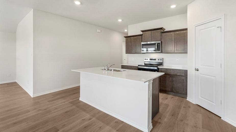 708 Rock Point Road, Josephine, TX 75135 Kitchen with wood-finish flooring, dark wood cabinetry, stainless steel appliances, and a central island with a white countertop
