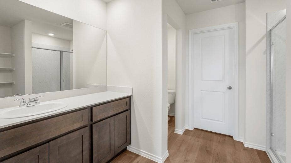 708 Rock Point Road, Josephine, TX 75135 Single vanity with an integrated sink, polished chrome faucet, wood-finish cabinetry, and a large wall mirror