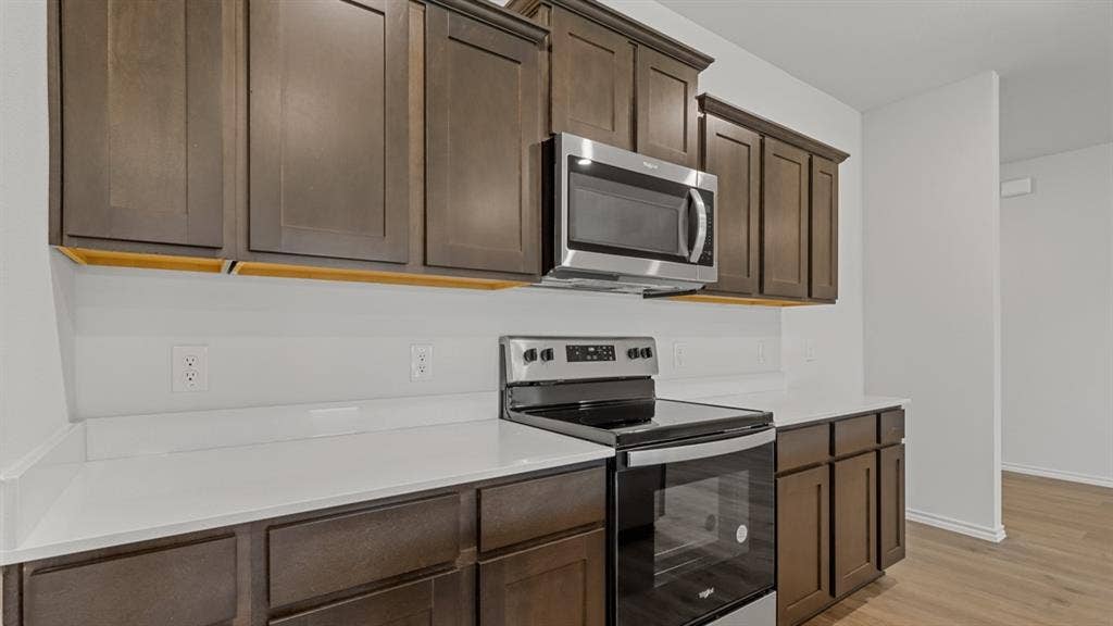 Kitchen featuring dark wood cabinetry, light-colored countertops, and a white subway tile backsplash