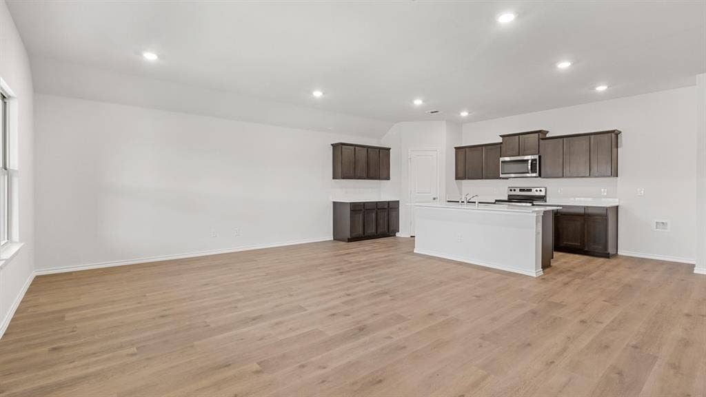 Open-concept living space featuring wood-finish flooring, recessed lighting, and a window for natural illumination
