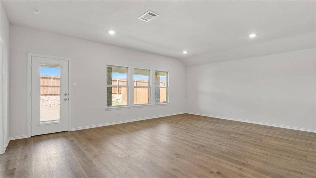 Spacious room with wood-finish flooring, recessed lighting, and white walls
