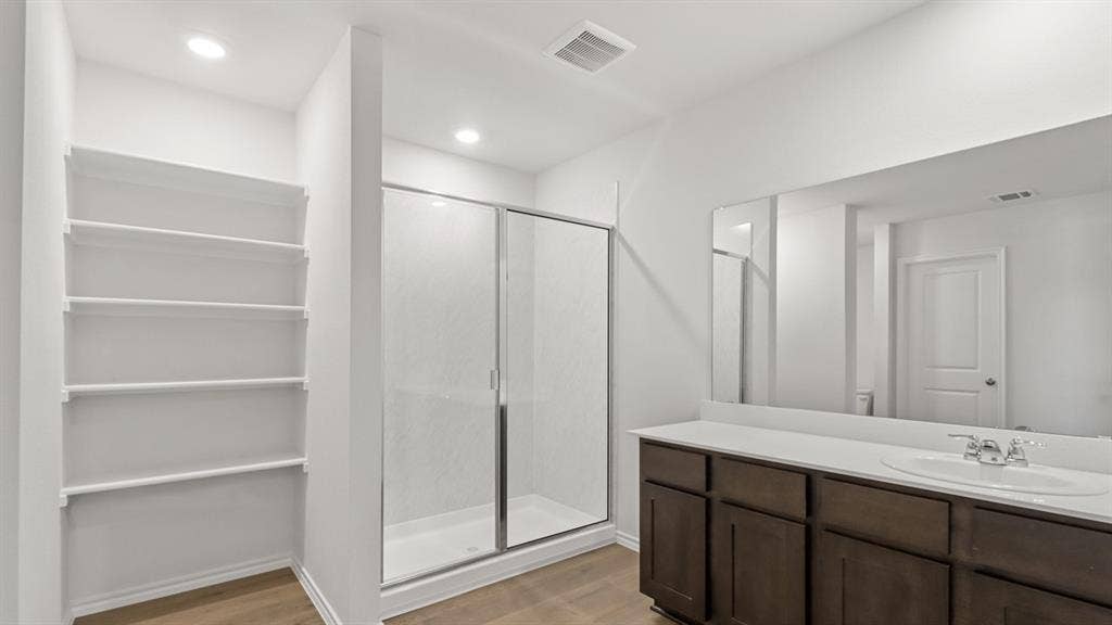 Contemporary bathroom featuring a spacious vanity with dark wood-finish cabinetry, a large integrated sink, and an expansive wall-mounted mirror