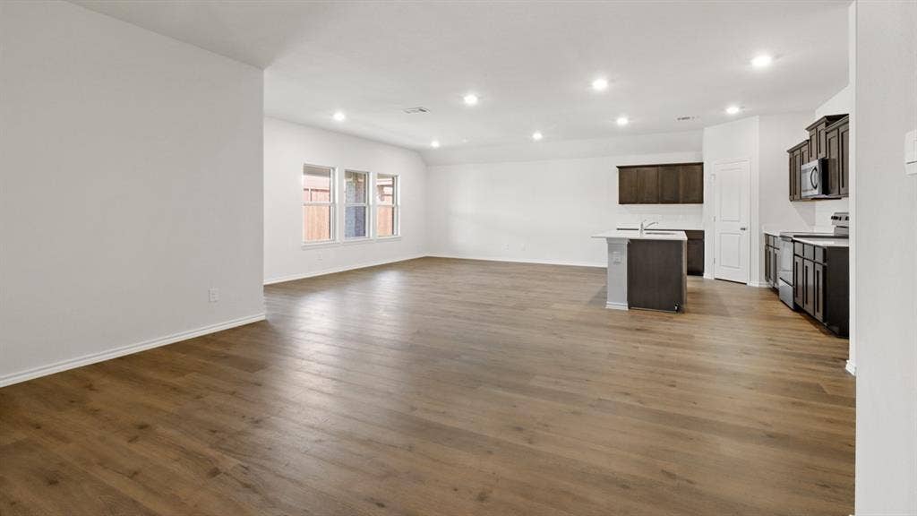 Expansive open-concept room featuring wood-finish flooring, recessed lighting, and a kitchen area
