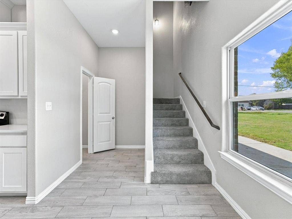 2312 Rogers Avenue, Lancaster, TX 75134 Interior space featuring wood-finish tile flooring, recessed lighting, carpeted staircase with a dark handrail, and large-format windows
