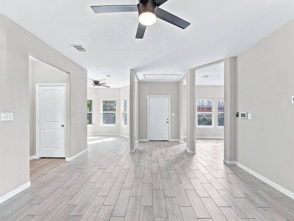 2312 Rogers Avenue, Lancaster, TX 75134 Interior space featuring wood-finish flooring, neutral wall paint, multi-blade ceiling fans with integrated lighting, and multiple windows with white trim