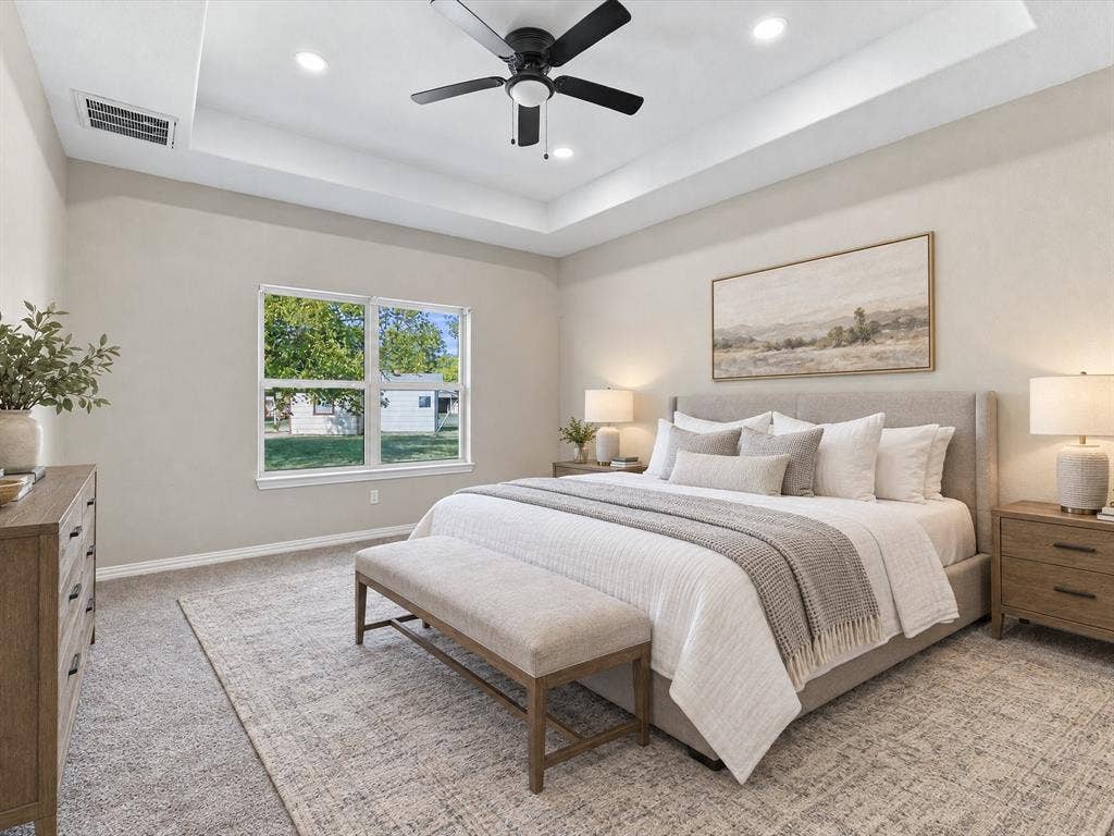 2312 Rogers Avenue, Lancaster, TX 75134 Virtually Staged Primary Bedroom featuring tray ceiling with recessed lighting and a central matte black ceiling fan, complemented by carpeting and a dual-pane window