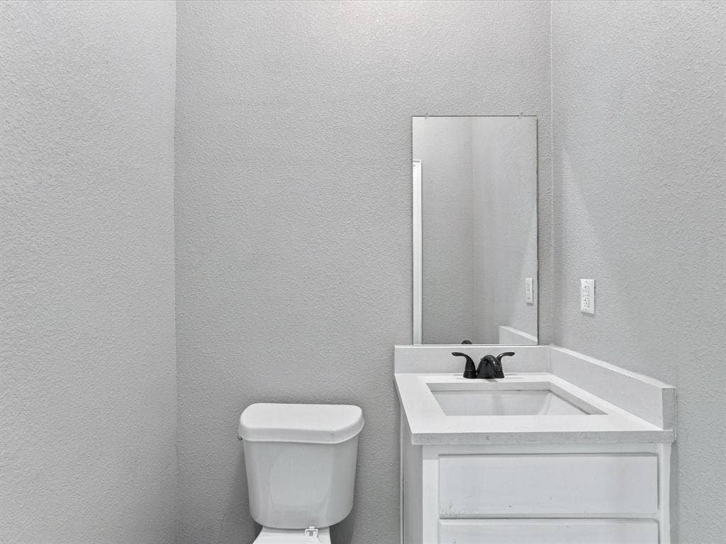 2312 Rogers Avenue, Lancaster, TX 75134 White vanity with rectangular integrated sink, neutral stone-composite countertop, matte black widespread faucet, and frameless wall-mounted mirror