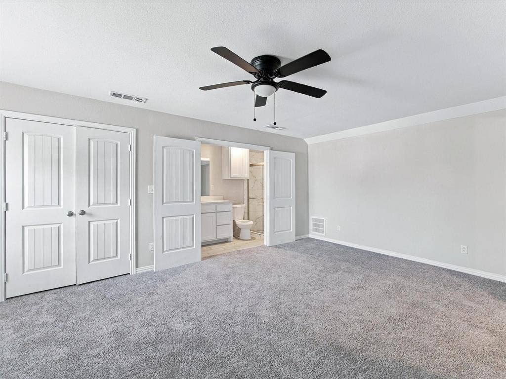 2312 Rogers Avenue, Lancaster, TX 75134 Upstairs secondary Primary Bedroom with neutral wall-to-wall carpeting, crisp crown molding, double-panel interior doors, and a centrally mounted ceiling fan with integrated lighting