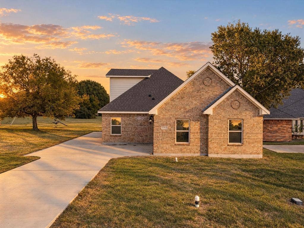 2312 Rogers Avenue, Lancaster, TX 75134 Brick exterior featuring a gabled roofline, concrete driveway, and rectangular windows