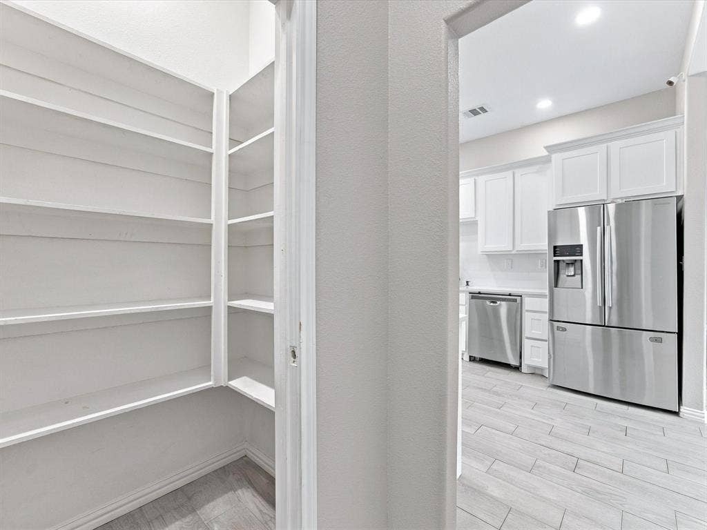 2312 Rogers Avenue, Lancaster, TX 75134 Walk-in pantry featuring built-in white shelving, tile flooring, stainless steel kitchen appliances, white cabinetry, and recessed lighting