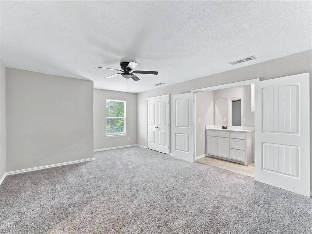 2312 Rogers Avenue, Lancaster, TX 75134 Upstairs secondary Primary Bedroom with neutral-toned interior featuring carpeted flooring, a ceiling fan with integrated lighting, multi-panel doors, and a vanity with a rectangular sink