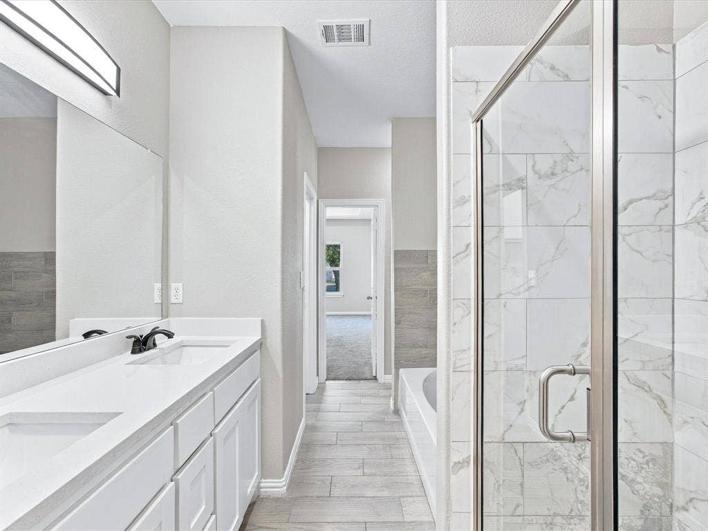 2312 Rogers Avenue, Lancaster, TX 75134 Bathroom featuring a dual-sink vanity with a white countertop, a walk-in shower with a glass enclosure and wall-tiling, a soaking tub, and tile flooring