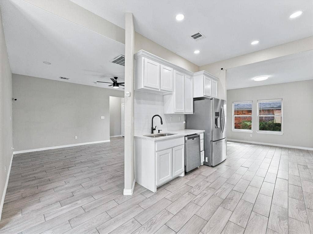 2312 Rogers Avenue, Lancaster, TX 75134 Kitchen featuring white cabinetry, wood-finish flooring, stainless steel appliances, and a matte black faucet
