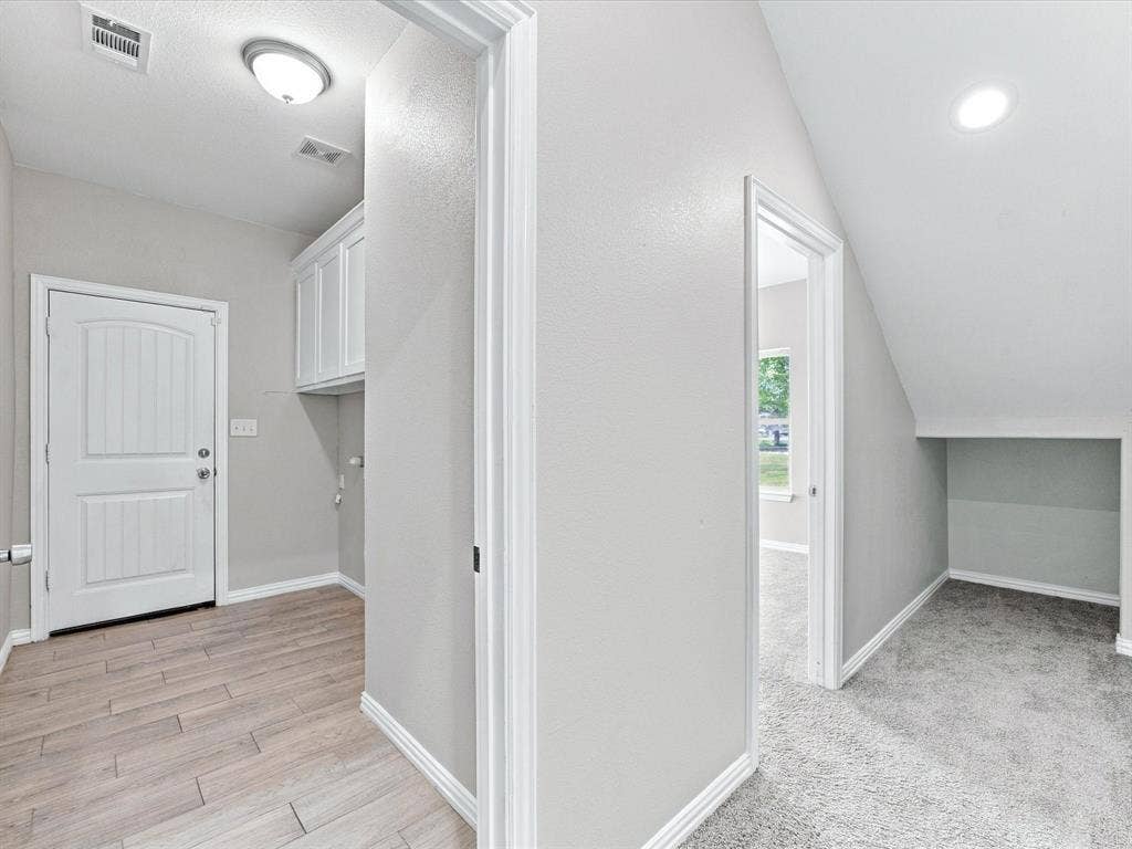 2312 Rogers Avenue, Lancaster, TX 75134 Hallway featuring wood-finish flooring, white upper cabinetry, ceiling-mounted lighting, and carpeted flooring