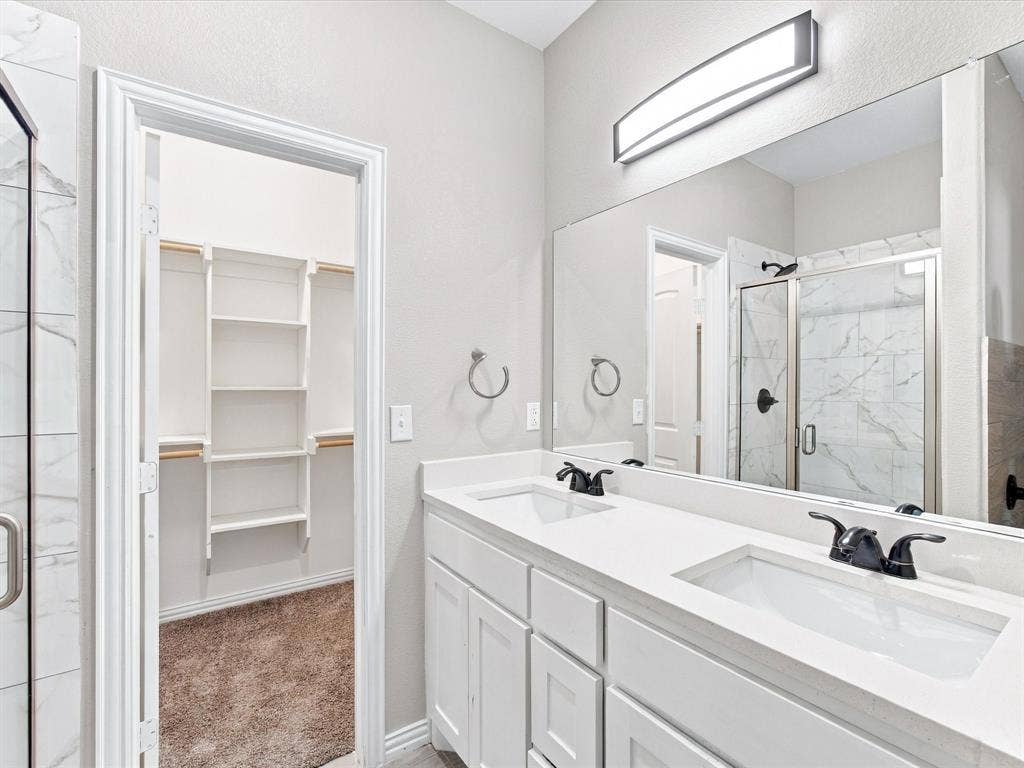 2312 Rogers Avenue, Lancaster, TX 75134 Double vanity with white cabinetry, light-toned countertop, and matte black fixtures, paired with a full-width mirror and integrated lighting