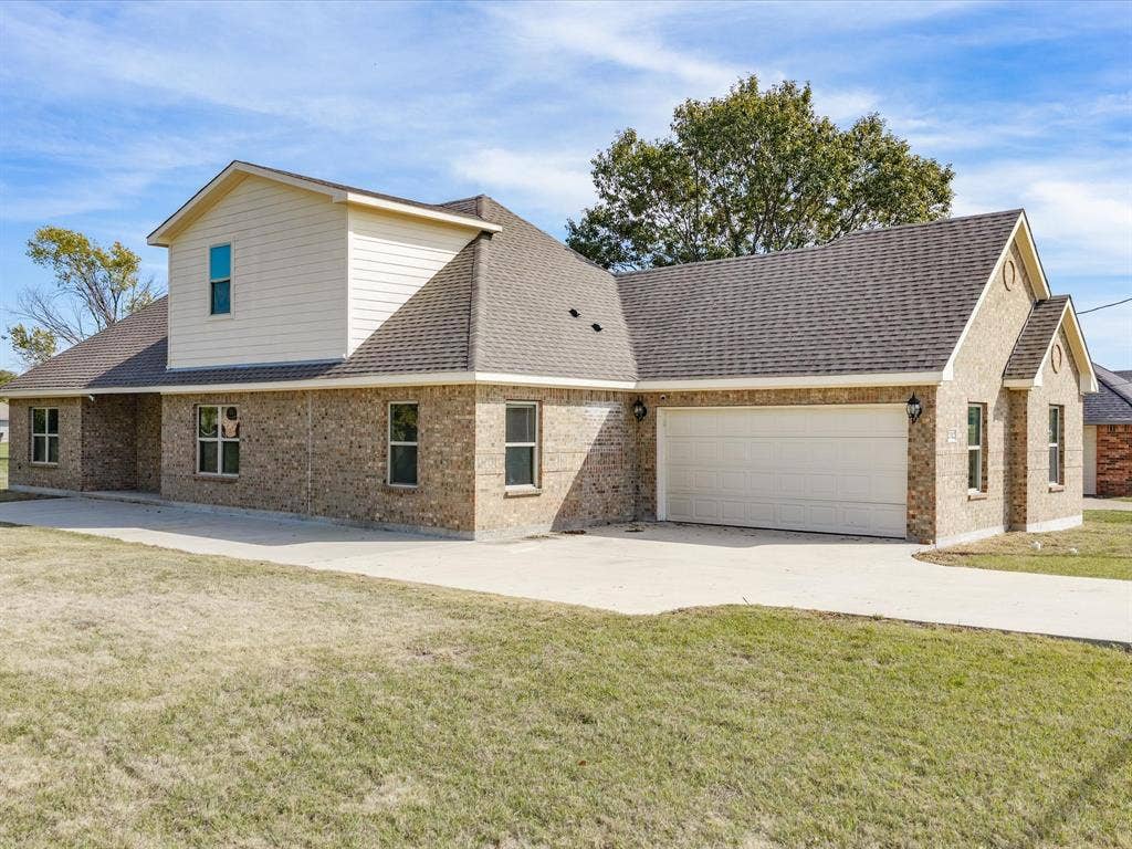 2312 Rogers Avenue, Lancaster, TX 75134 Multi-level exterior featuring a brick facade, siding accents, a pitched roof, and an attached two-car garage