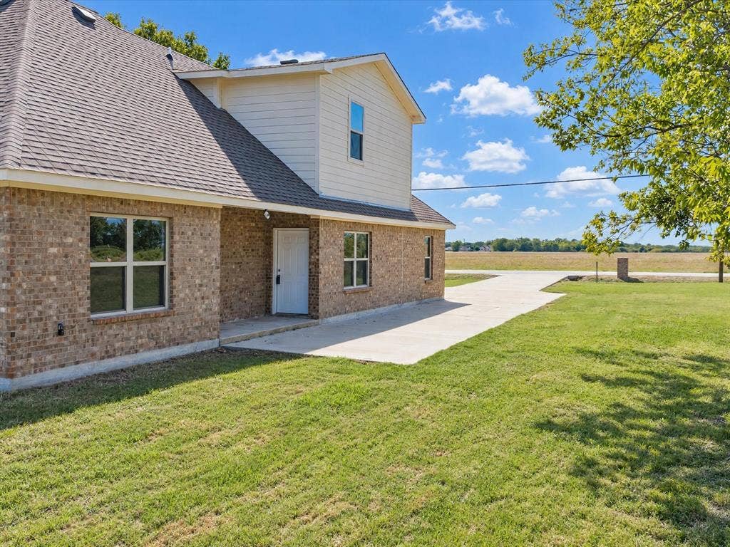 2312 Rogers Avenue, Lancaster, TX 75134 Brick and siding exterior featuring a concrete walkway, multi-gable roofline, and expansive surrounding grounds